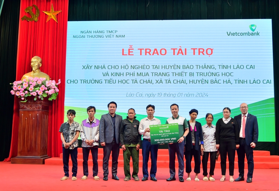 Ông Lê Hoàng Tùng - Phó Tổng Giám đốc Vietcombank (thứ 5 từ phải sang) cùng ông Đặng Việt Hùng - Giám đốc Vietcombank Lào Cai (ngoài cùng bên phải) trao biểu trưng hỗ trợ kinh phí xây dựng nhà cho 6 hộ gia đình khó khăn tại huyện Bảo Thắng, tỉnh Lào Cai.